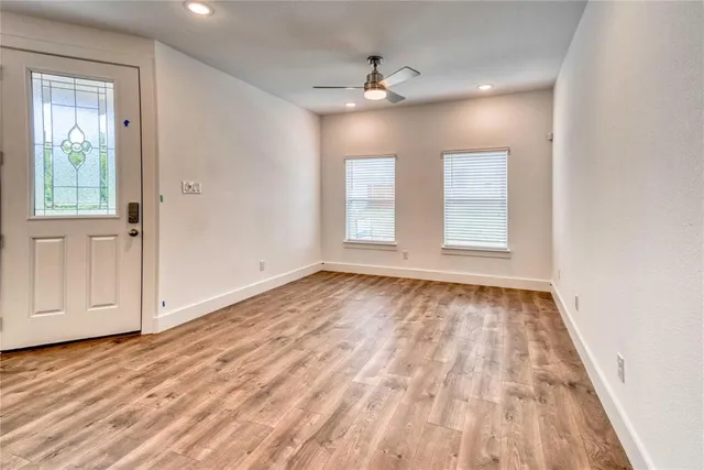 a view of an empty room with wooden floor and window