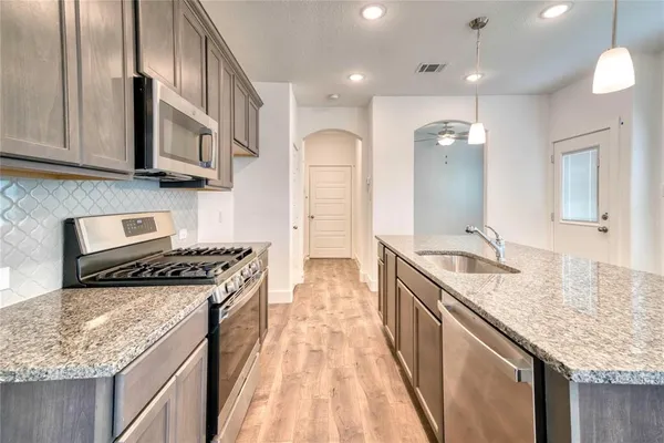 a kitchen with stainless steel appliances granite countertop a sink stove and refrigerator