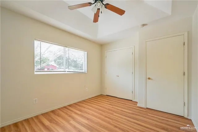a view of empty room with wooden floor and fan