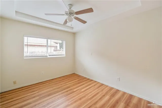 an empty room with wooden floor chandelier fan and windows