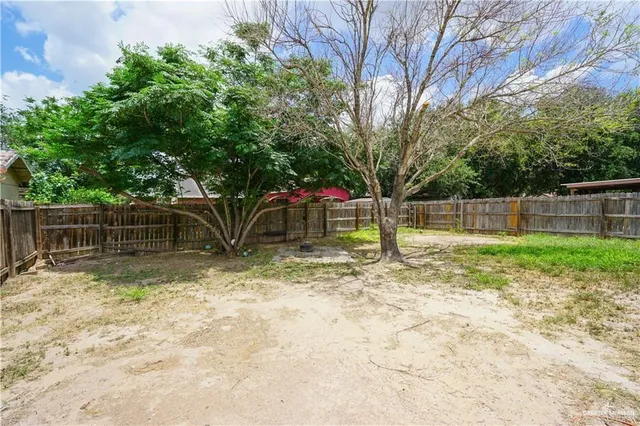 a view of backyard with wooden fence and a large tree