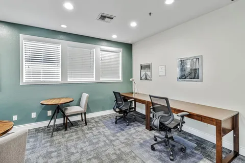 a view of a workspace with furniture and a window