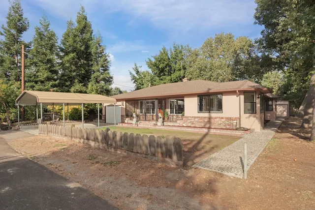 a front view of a house with a yard and trees