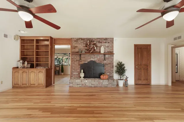 a view of a livingroom with wooden floor a ceiling fan and windows