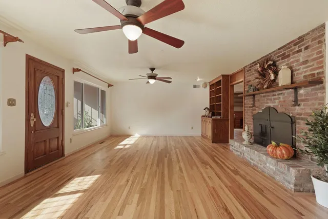 a view of an empty room with a window and wooden floor