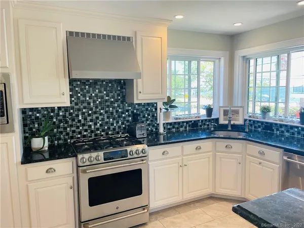a kitchen with granite countertop white cabinets and white appliances