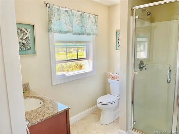 a bathroom with a granite countertop toilet a sink and a shower