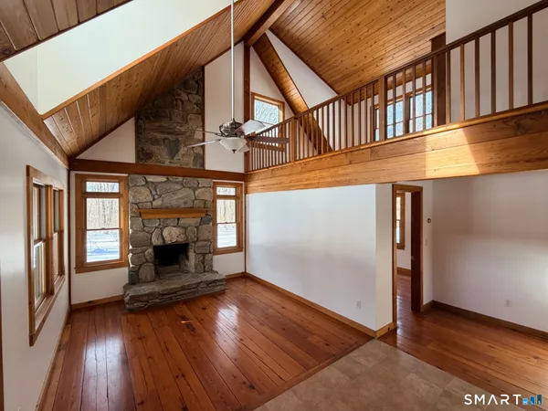 an empty room with wooden floor fireplace and windows