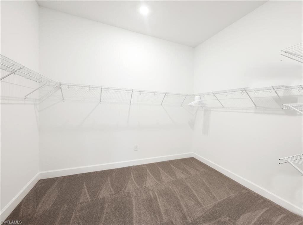 8448 Rosa Court Naples, FL 34114 - Photo 17 of 24 Spacious walk-in closet featuring white wire shelving, bright white walls, recessed ceiling lighting, and soft grey carpeting