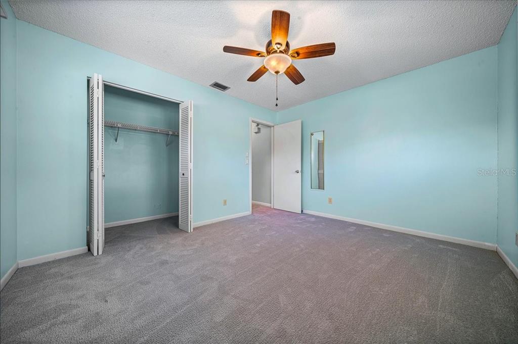 8702 Southwest 94 Street, Unit A Ocala, FL 34481 - Photo 16 of 55 an empty room with a ceiling fan and carpet