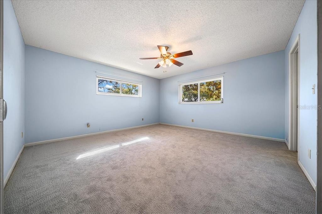 8702 Southwest 94 Street, Unit A Ocala, FL 34481 - Photo 19 of 55 an empty room with windows and a ceiling fan