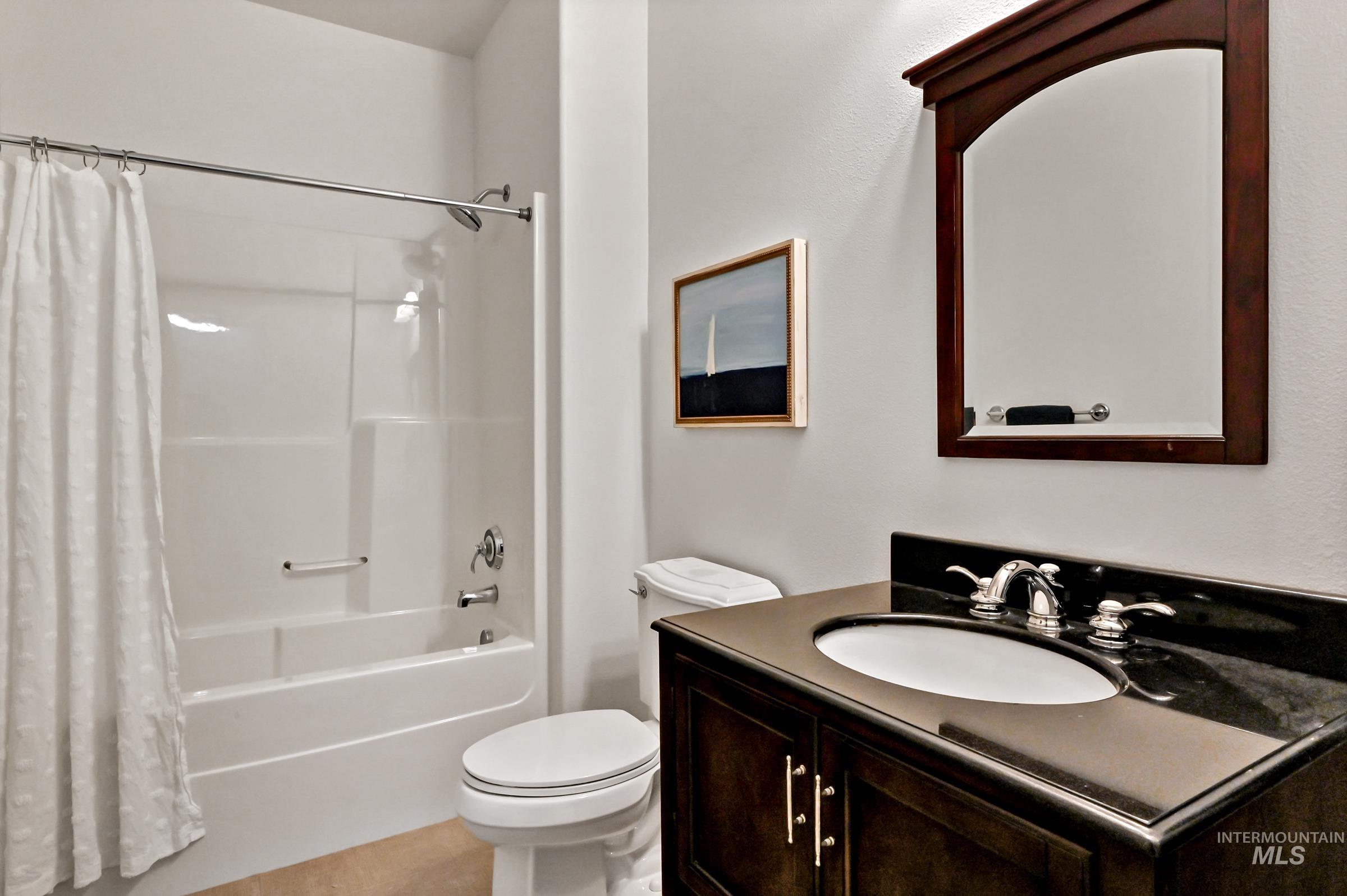 2476 North Bogus Basin Road Boise, ID 83702 - Photo 31 of 48 First-level bathroom with wood vanity, framed mirror, and tile flooring. Tub/shower insert. Functional design with clean finishes.