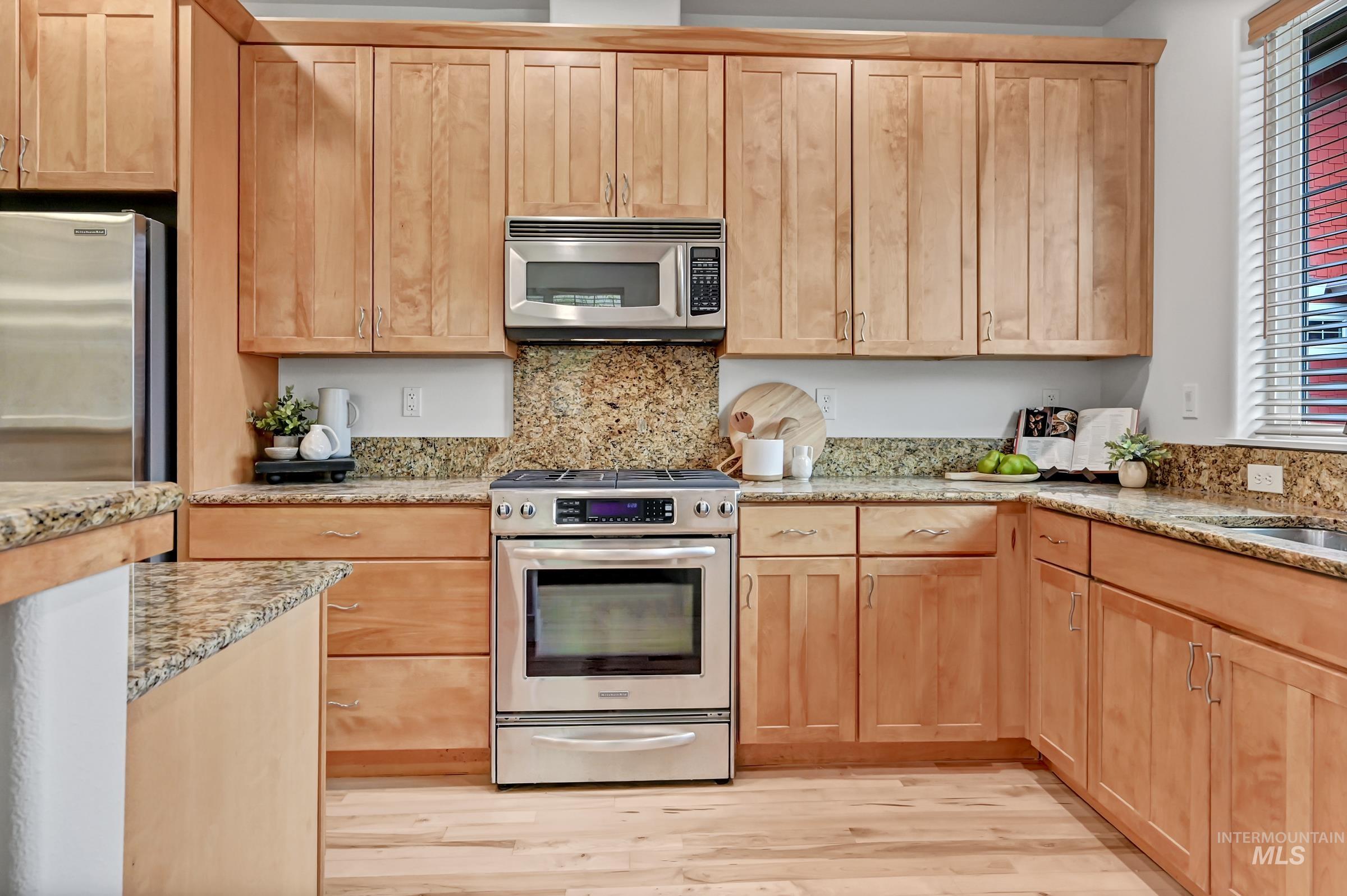 2476 North Bogus Basin Road Boise, ID 83702 - Photo 8 of 48 Kitchen with wood cabinets, granite counters, and stainless appliances. Efficient layout with an island and large windows.