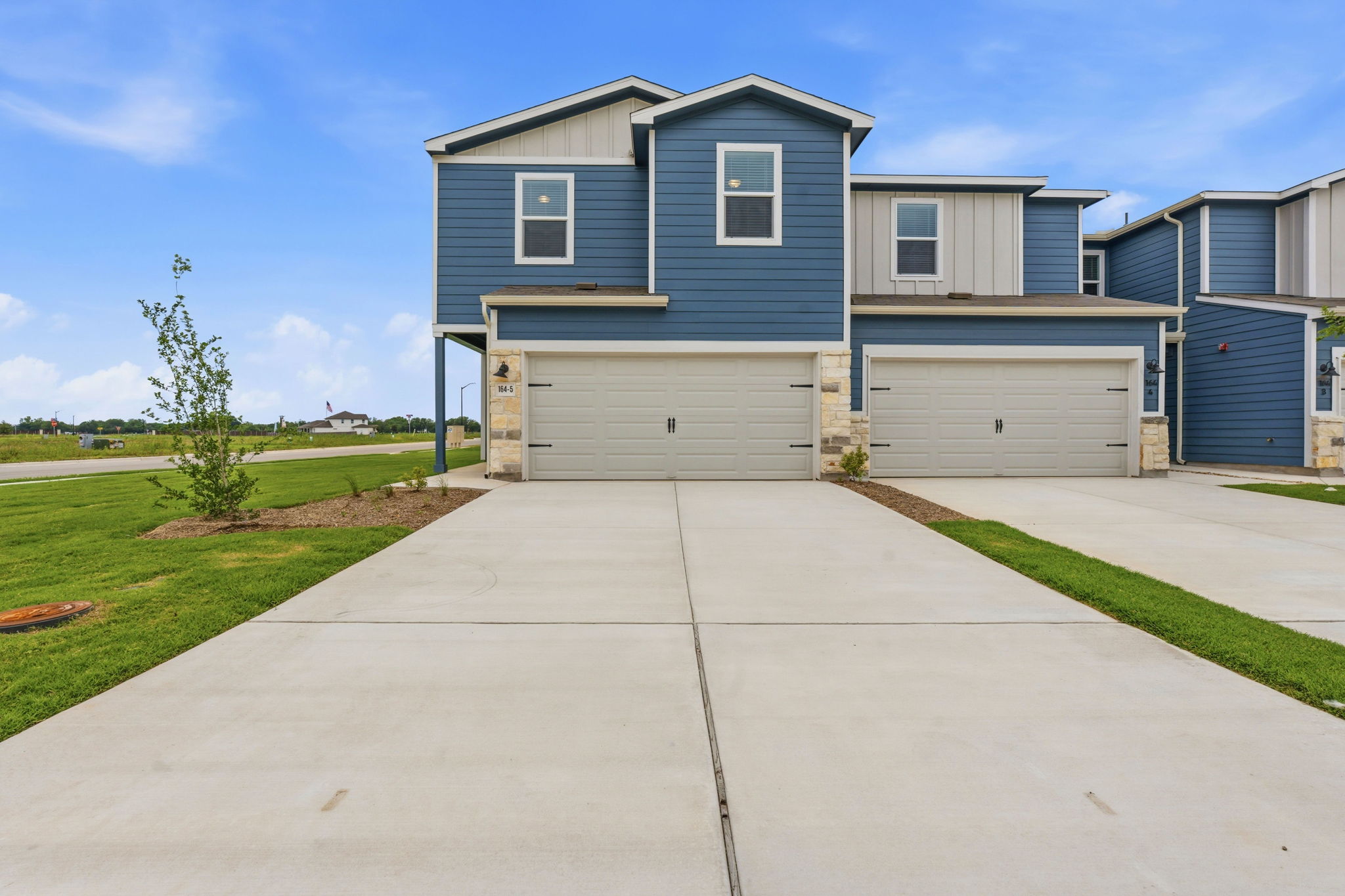 Contemporary townhome facade featuring blue siding, light gray siding accents, and stone veneer detailing