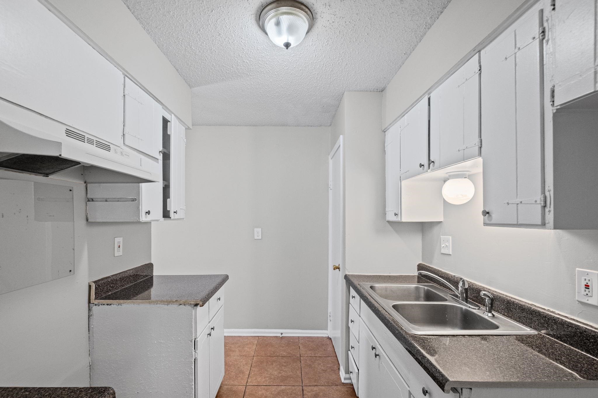 3580 Ramill Road Memphis, TN 38128 - Photo 9 of 24 Kitchen featuring dark countertops, a textured ceiling, light tile patterned floors, and white cabinetry
