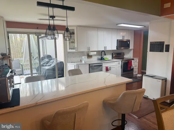 a kitchen with stainless steel appliances kitchen island granite countertop a refrigerator a stove and white cabinets