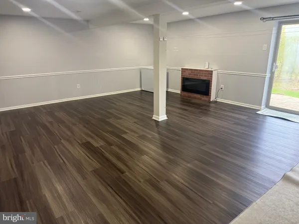 an empty room with wooden floor fireplace and windows