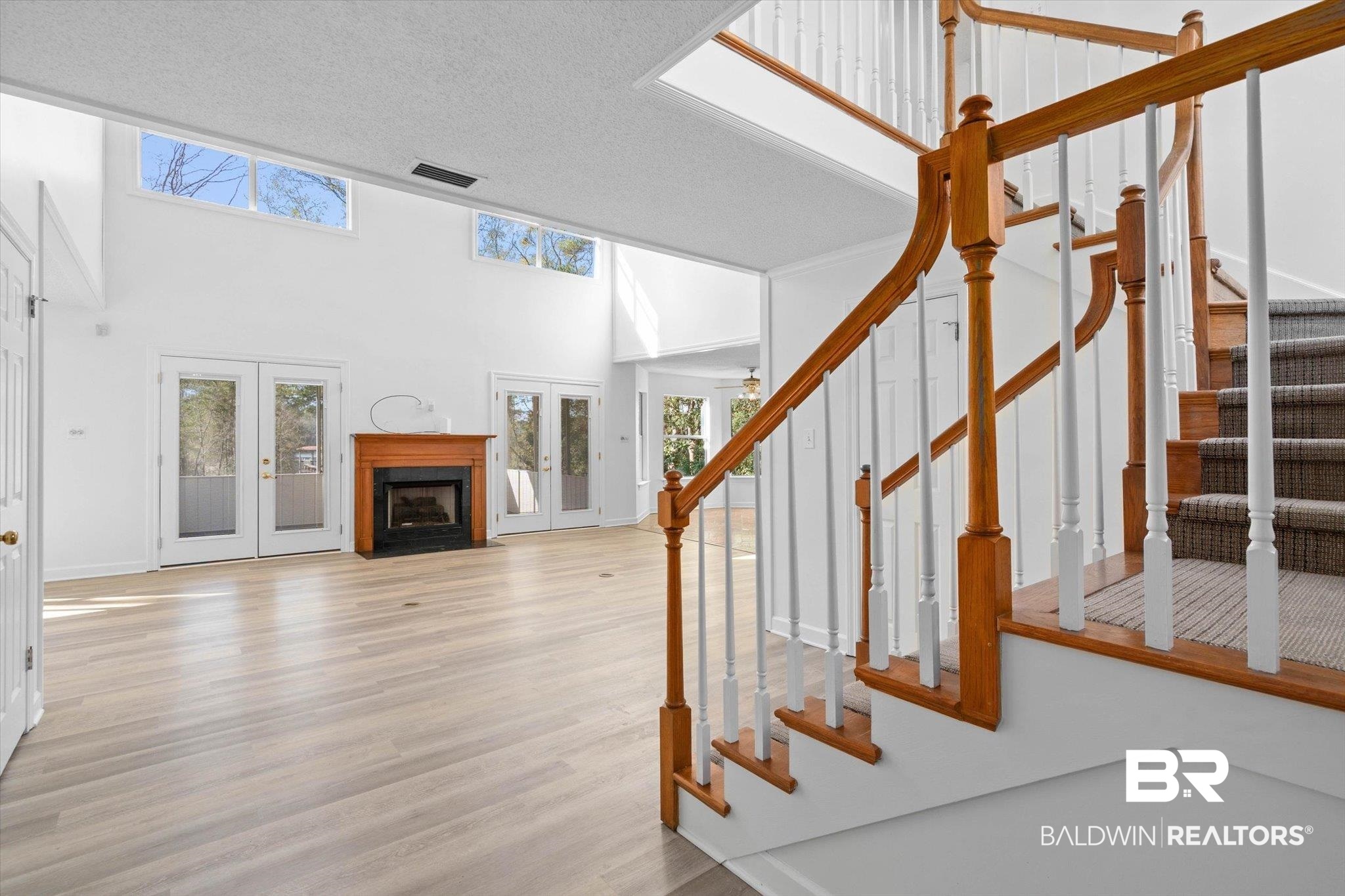 3847 Riviere Du Chien Road Mobile, AL 36693 - Photo 7 of 51 Stairway featuring a fireplace with flush hearth, a high textured ceiling, wood finished floors, and french doors