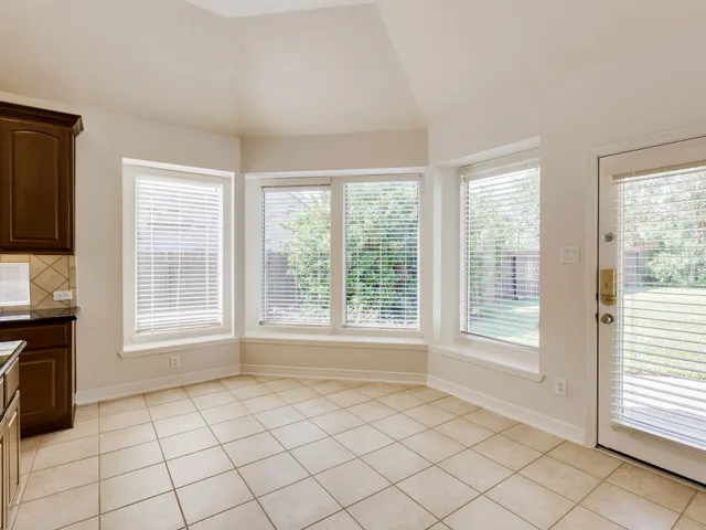 a view of an empty room with a window and a kitchen