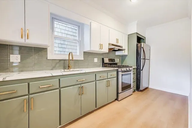 a kitchen with a sink cabinets stainless steel appliances and a window