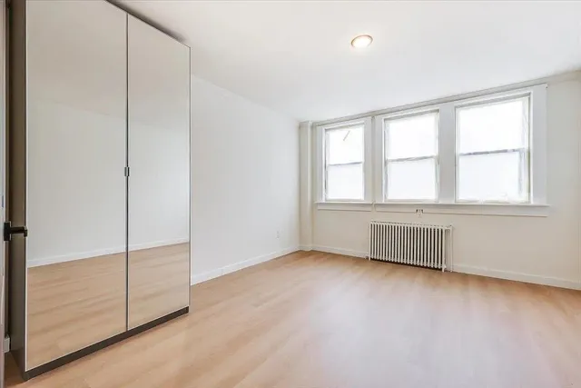 an empty room with wooden floor and windows with curtains