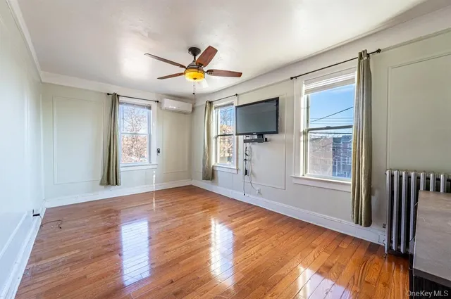 a view of a livingroom with a flat screen tv wooden floor and a window
