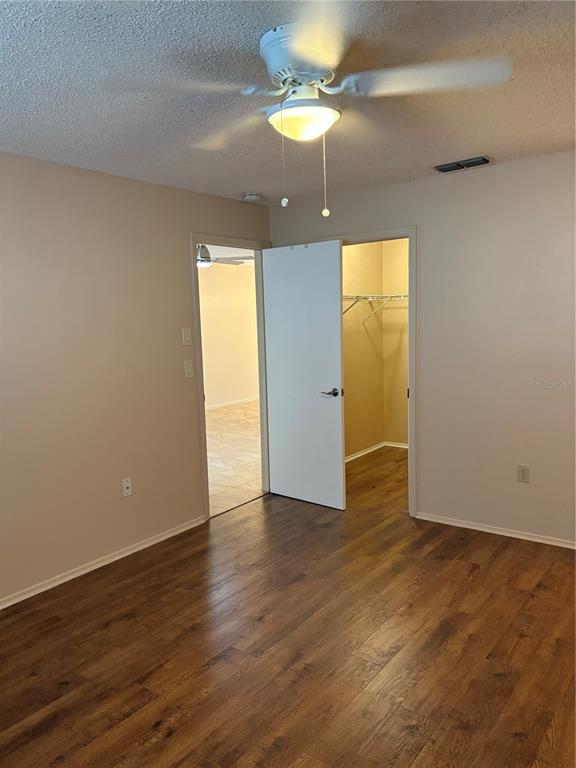 13250 Ridge Road, Unit 16 Largo, FL 33778 - Photo 19 of 32 an empty room with wooden floor chandelier fan and windows