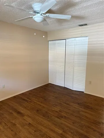 an empty room with wooden floor fan and windows