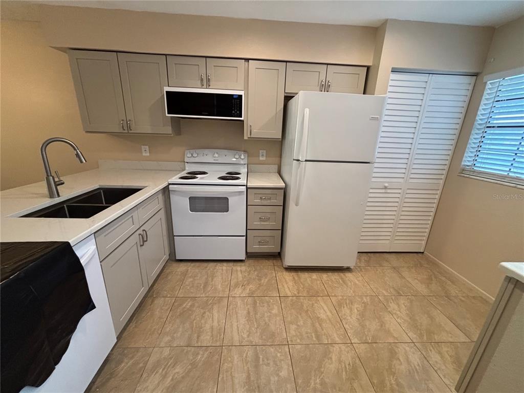13250 Ridge Road, Unit 16 Largo, FL 33778 - Photo 3 of 32 a white kitchen with sink a refrigerator and a stove