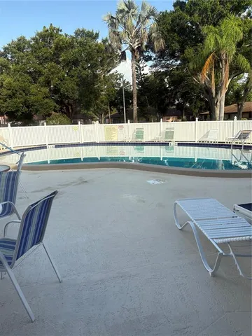 a view of swimming pool with lawn chairs and plants