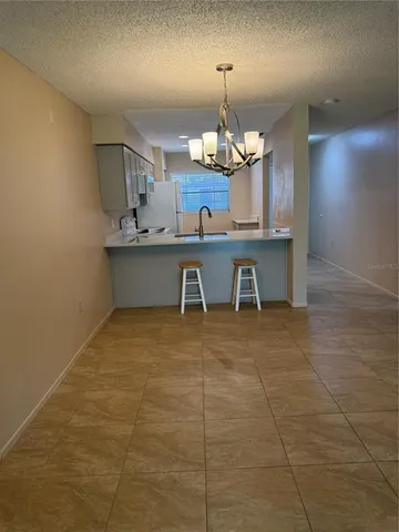 a view of a kitchen with a sink and chandelier stainless steel appliances