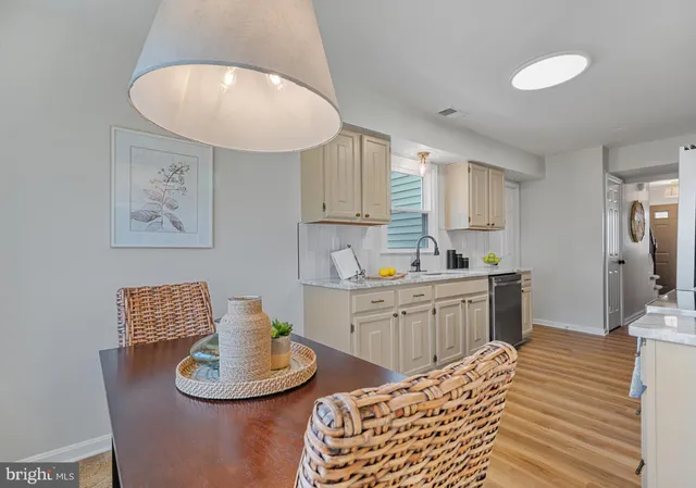 a kitchen with stainless steel appliances granite countertop a stove top oven a sink dishwasher and white cabinets with wooden floor