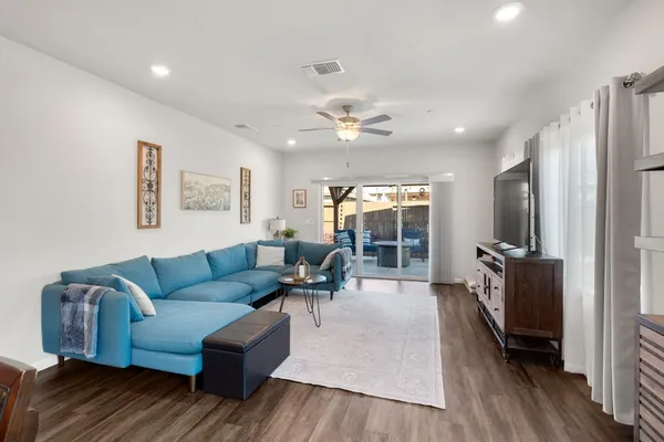 a living room with furniture a ceiling fan and a flat screen tv