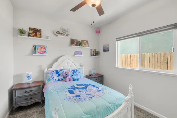 a view of an empty room with wooden floor and a ceiling fan