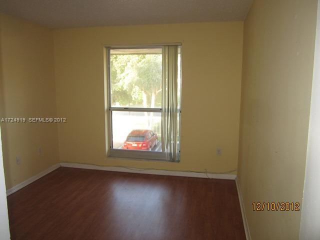 13783 Southwest 66th Street, Unit 219A Miami, FL 33183 - Photo 7 of 10 an empty room with wooden floor and windows