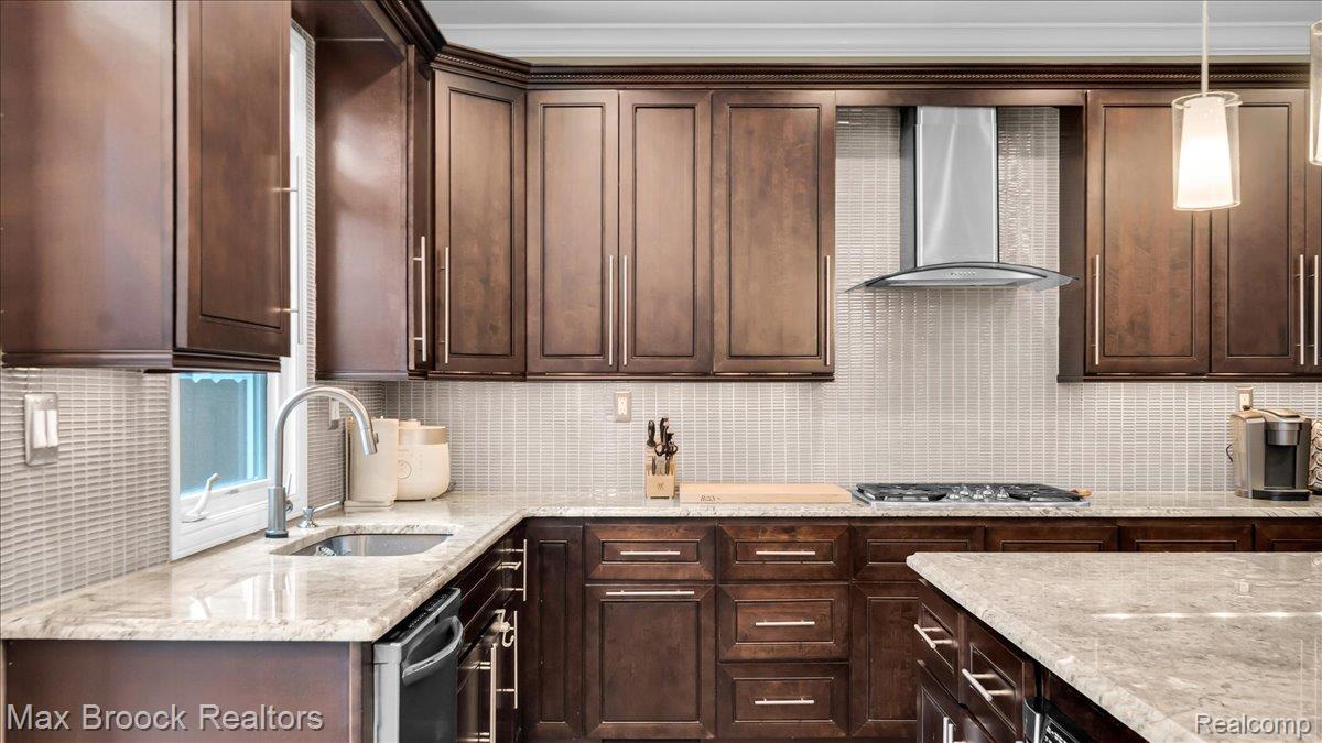 2253 Pembroke Road Birmingham, MI 48009 - Photo 16 of 56 U-shaped kitchen featuring wood cabinetry, light-toned stone countertops, a tile backsplash, stainless steel range hood, and a kitchen island
