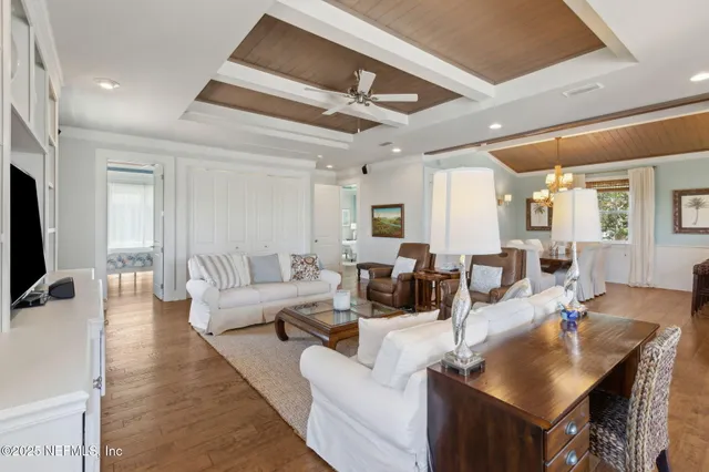 a living room with furniture a flat screen tv and a chandelier