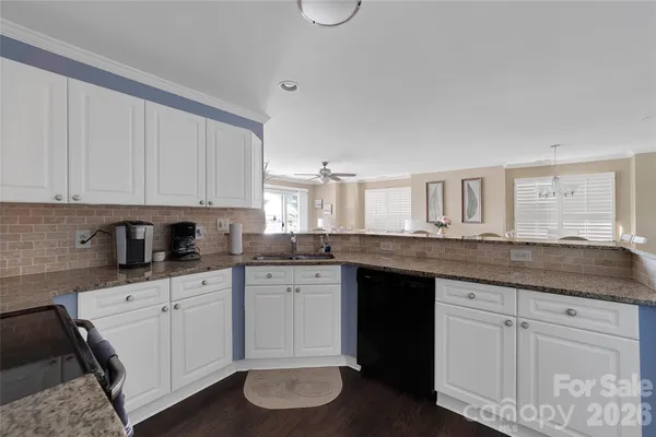 a kitchen with granite countertop a sink white cabinets and wooden floor