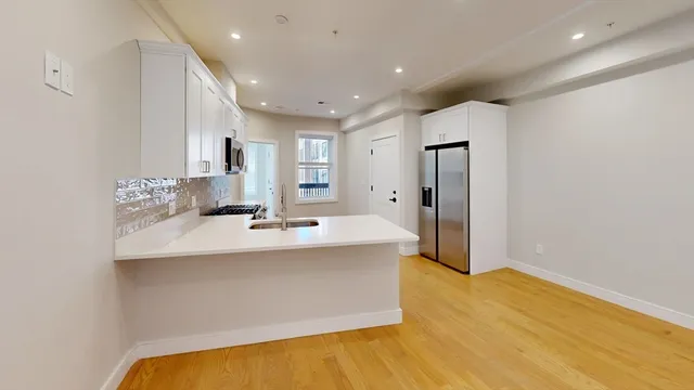 a view of a kitchen with kitchen island a sink stainless steel appliances and cabinets