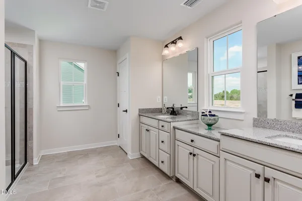 a bathroom with double sink large mirror and a window