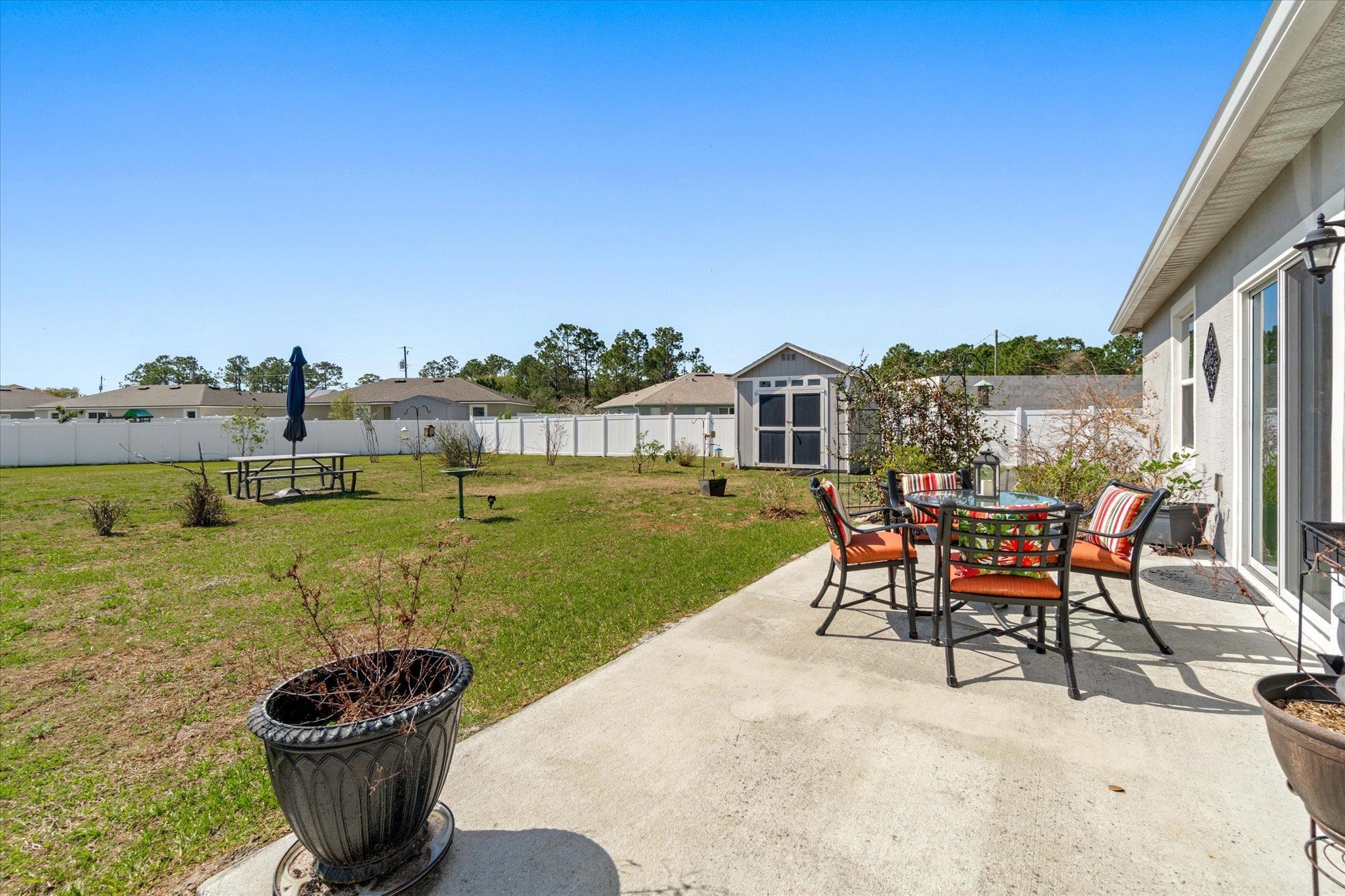 1 Frenora Lane Palm Coast, FL 32137 - Photo 26 of 43 Fenced backyard featuring a patio, outdoor dining space, and a storage shed