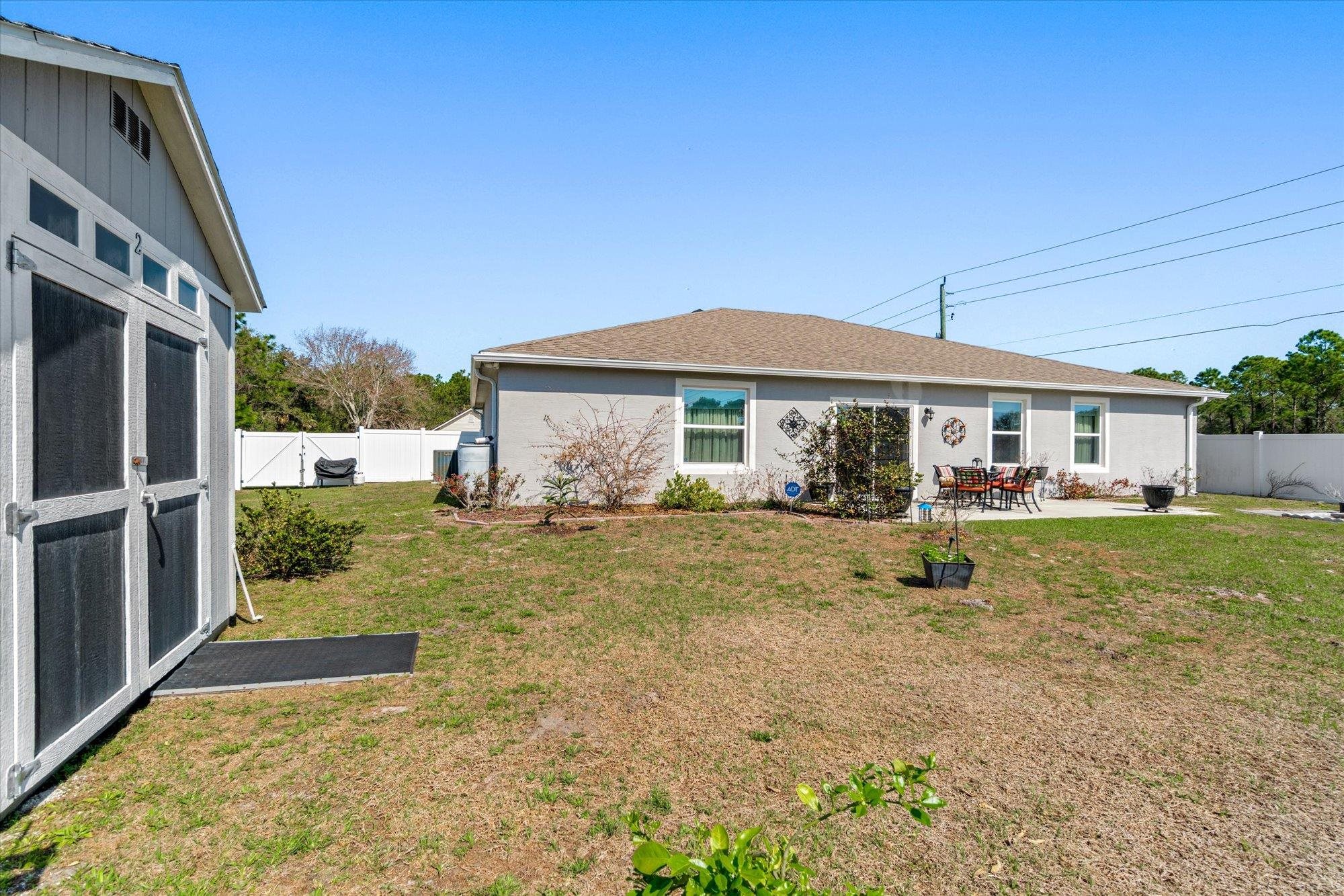 1 Frenora Lane Palm Coast, FL 32137 - Photo 30 of 43 Rear view of house with a fenced backyard, a patio area, stucco siding, and an outbuilding