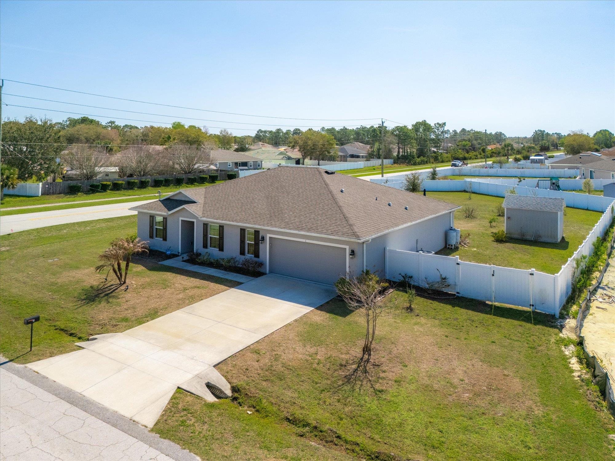 1 Frenora Lane Palm Coast, FL 32137 - Photo 34 of 43 View of front of house featuring an attached garage, concrete driveway, a shingled roof, a gate, and a residential view