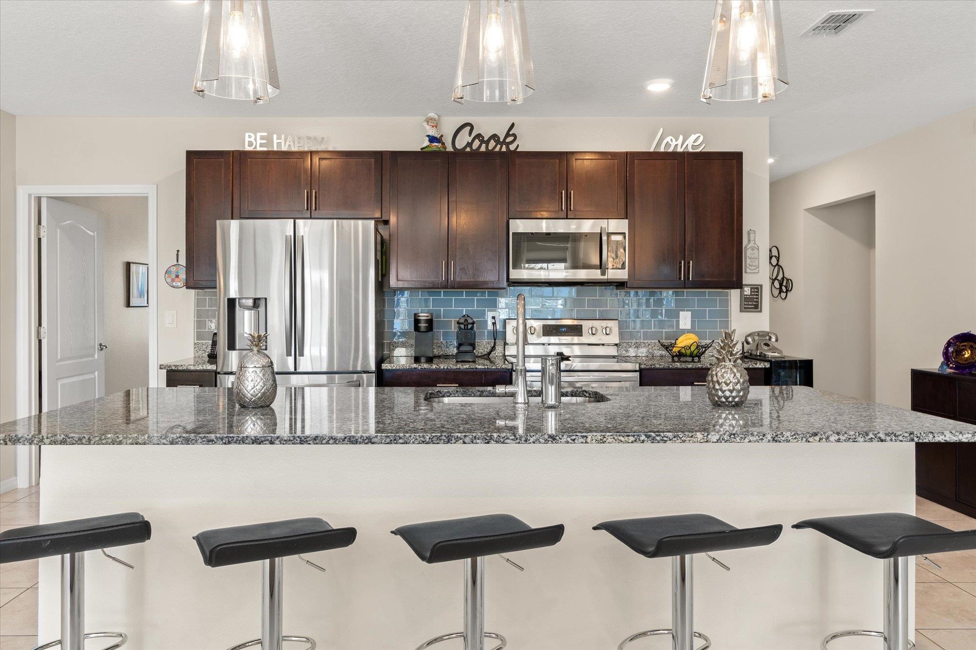 1 Frenora Lane Palm Coast, FL 32137 - Photo 6 of 43 Kitchen with a breakfast bar, stainless steel appliances, light tile patterned floors, and backsplash