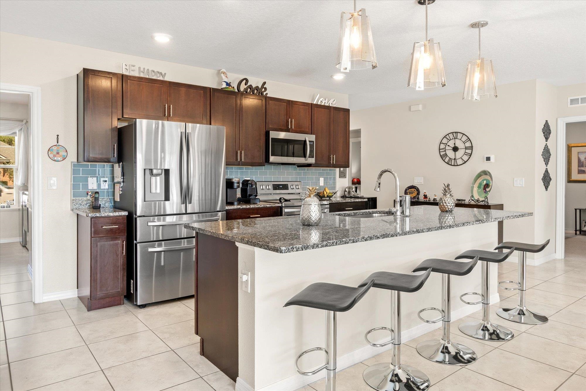 1 Frenora Lane Palm Coast, FL 32137 - Photo 8 of 43 Kitchen with dark stone counters, stainless steel appliances, light tile patterned floors, and a kitchen breakfast bar