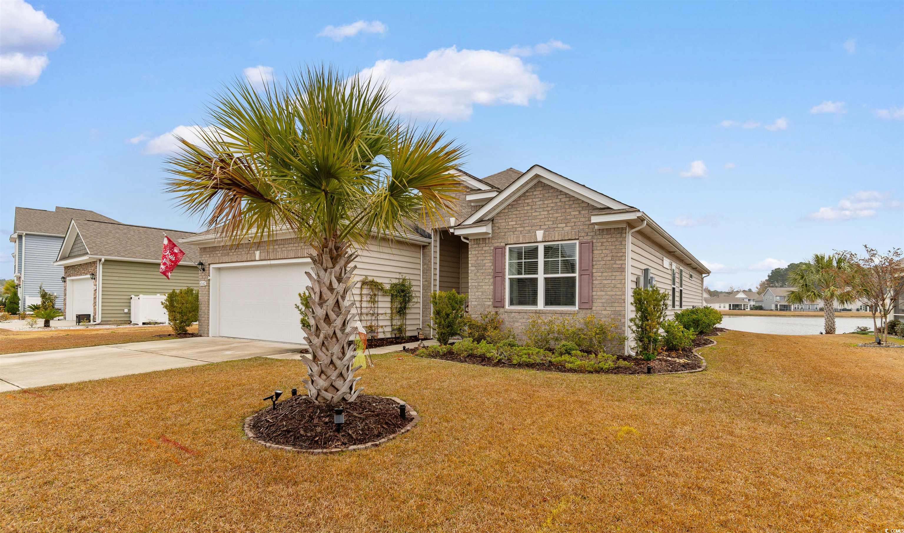 Single story home featuring concrete driveway, brick siding, a front yard, and an attached garage