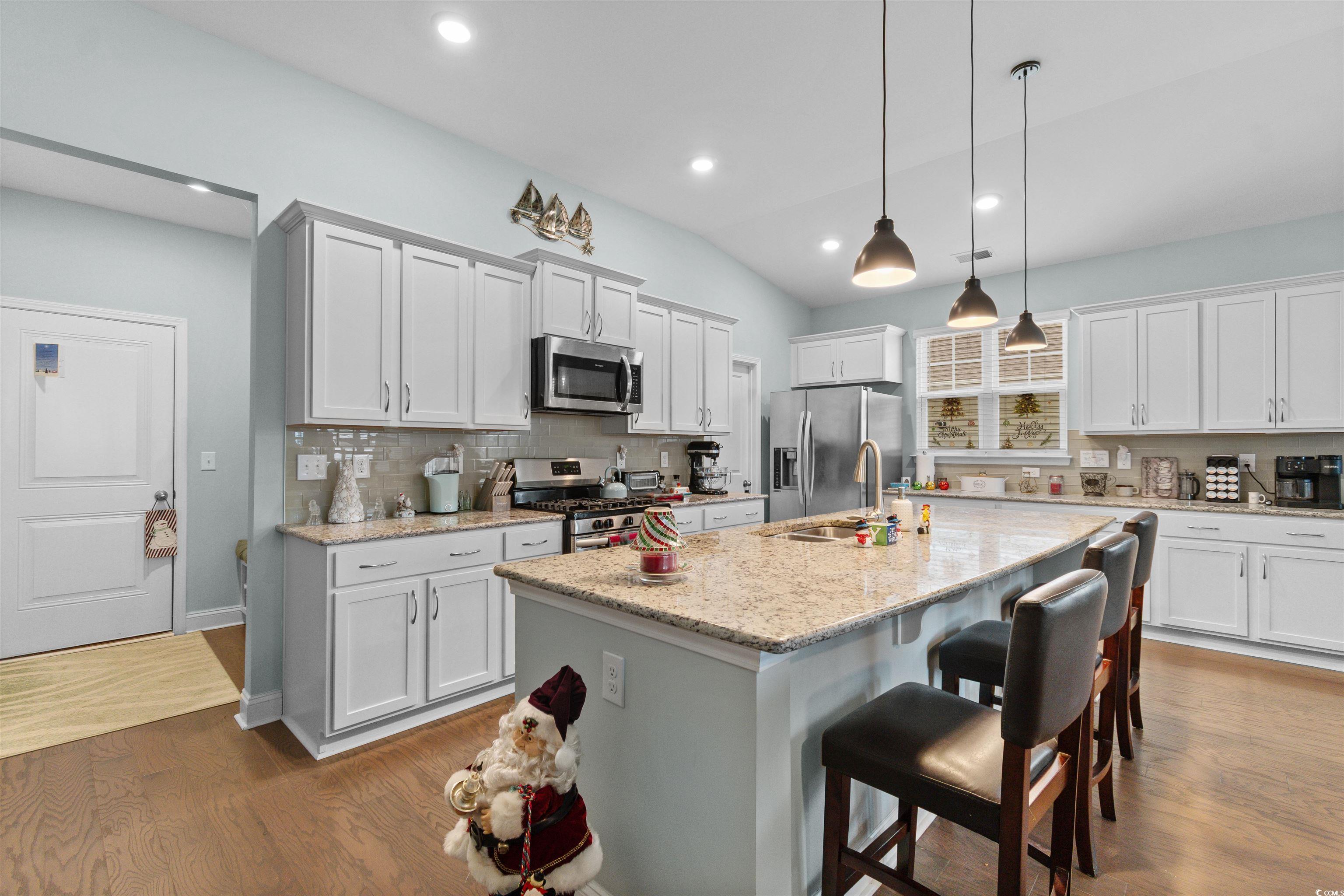 4842 Timberlake Drive Myrtle Beach, SC 29588 - Photo 15 of 38 Kitchen featuring a kitchen breakfast bar, lofted ceiling, white cabinetry, decorative light fixtures, and a kitchen island with sink