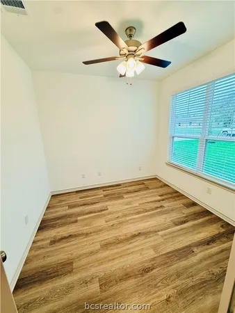 a view of a room with a ceiling fan and wooden floor