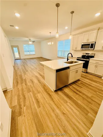 a kitchen with stainless steel appliances granite countertop a sink a stove and a wooden floors