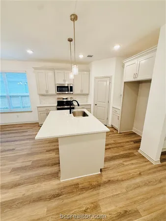 a view of a kitchen with kitchen island a sink wooden floor and a refrigerator